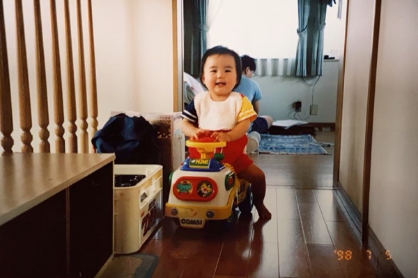 日付が焼き込まれた1998年のフィルム写真。廊下でおもちゃの車に乗る赤ちゃん